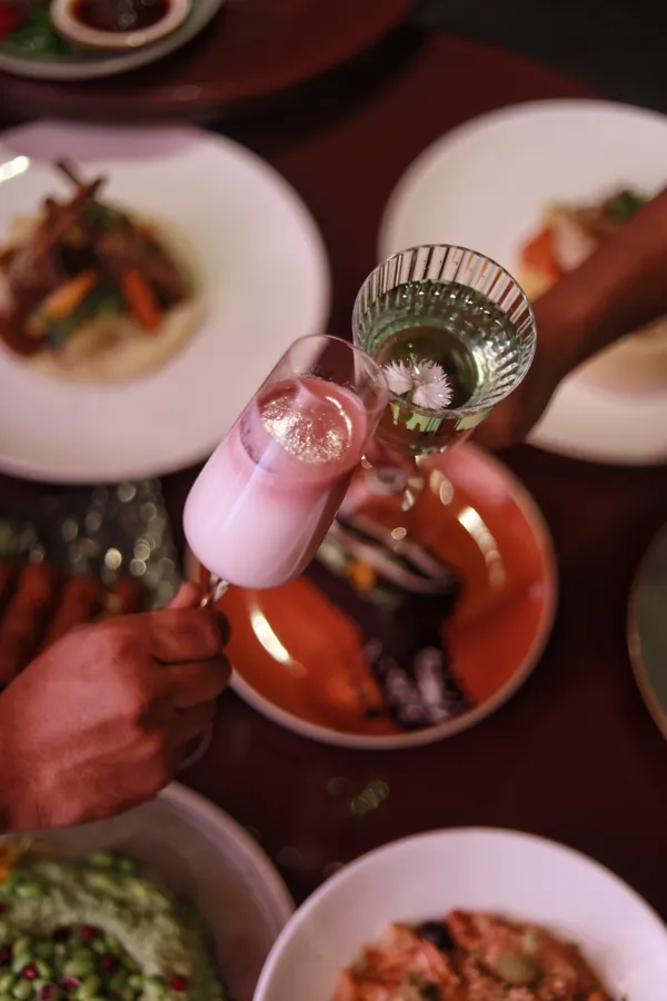 Raising a pink cocktail at the dinner table