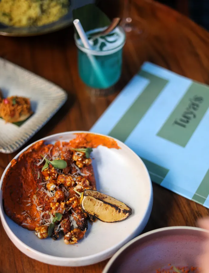 A plated dish with accompaniments and a blue drink